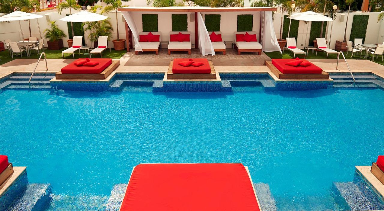 Poolside cabanas with red cushions at S Hotel Kingston rooftop terrace